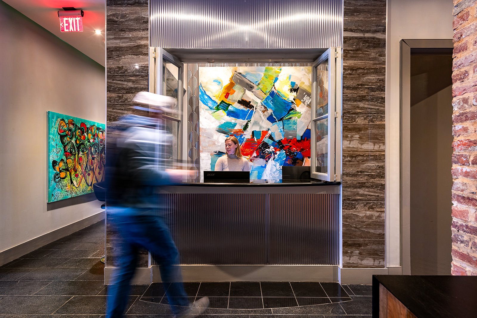 People at a hotel reception desk with colorful abstract paintings and modern decor.